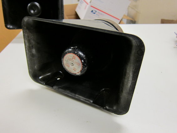 Black siren speaker with a circular red and white label