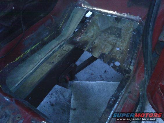 Close-up of a vehicle's floor pan area with metal cut out and being repaired