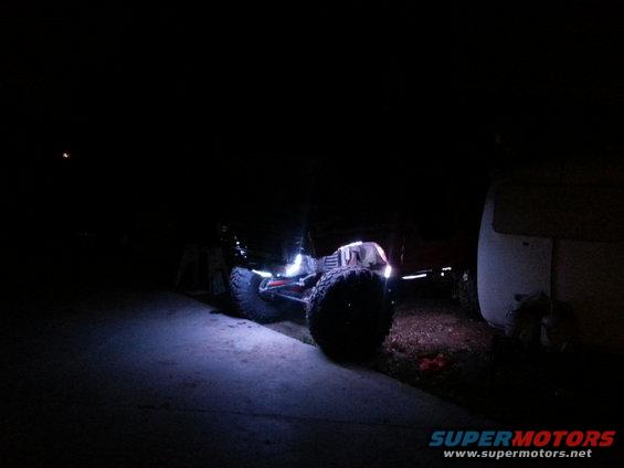 Off-road vehicle with large tires and underglow lights at night