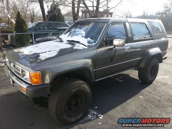 Gray Toyota 4Runner with snow on the hood. Another vehicle is parked behind it