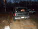 1986 Ford Bronco - Rear view of a black 1986 Ford Bronco, showing its spare tire mount and a second vehicle in the background.