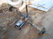 1986 Ford Bronco - A vehicle's rear axle assembly is shown supported by a jack on the ground, with a spare tire and tools in the background.