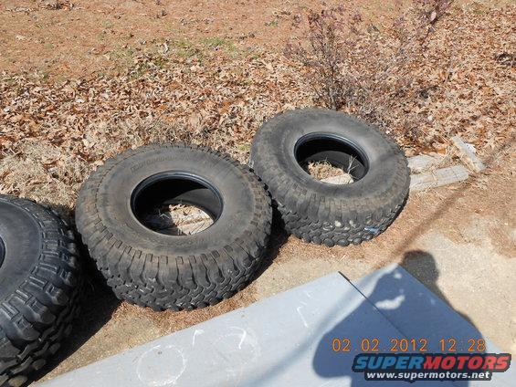 Three off-road tires on the ground, one partially visible on the left