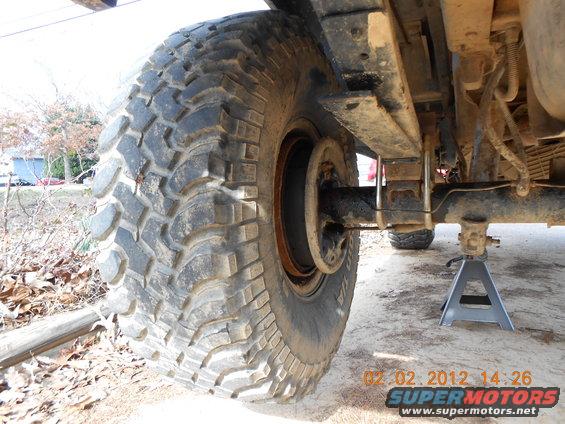 Tire and rear axle assembly on jack stands, showing leaf spring suspension and brake drum