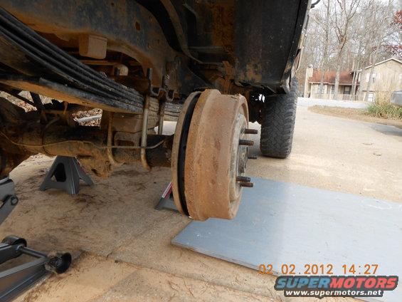 Rear axle and drum brake assembly on jack stands, showing leaf springs and wheel studs