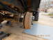 1986 Ford Bronco - The rear axle and drum brake assembly are supported by jack stands, with leaf springs and wheel studs visible.