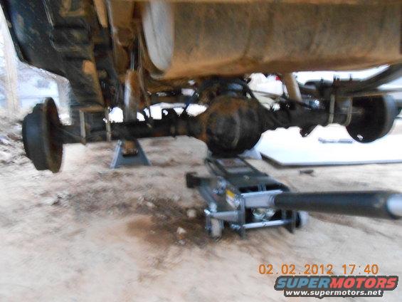 Vehicle rear axle assembly on jack stands with a floor jack underneath