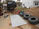 1986 Ford Bronco - A black SUV is undergoing maintenance with its rear axle removed, surrounded by spare tires and tools.