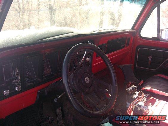 1979 Ford Bronco interior, red dashboard, aftermarket steering wheel, snow on windshield
