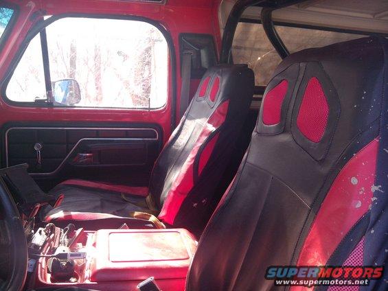 Interior shot of a red truck cab, showing custom black and red seats, door panel, and center console