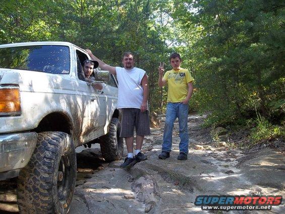 1990 Ford Bronco on a rocky trail with three people standing nearby