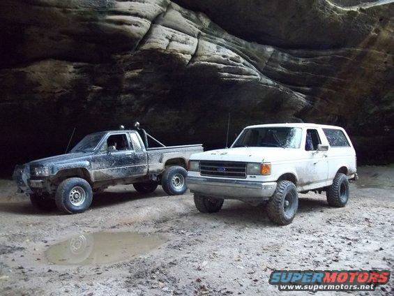 White Ford Bronco and black Toyota pickup truck parked in a rocky alcove