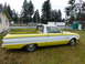 1961 Ford Ranchero - A two-tone pickup truck with a yellow and white exterior is parked on a grassy area.