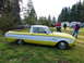1961 Ford Ranchero - 1961 Ford Ranchero pickup truck in yellow and white, with people standing around it outdoors.
