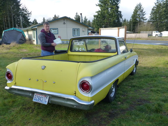 Yellow and silver pickup truck with a man holding papers, parked on grass. "FOR SALE 300" is written on the rear window