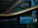 1961 Ford Ranchero - A close-up view of a blue engine component with metal hoses and grime.