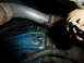 1961 Ford Ranchero - Close-up view of an exhaust pipe and a blue engine component with hose clamps.