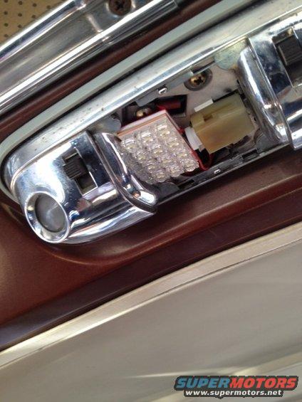 Close-up of a car's interior dome light fixture, showing a modern LED bulb replacement
