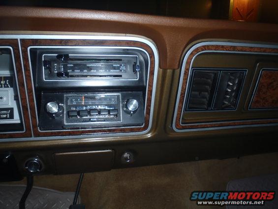 Brown dashboard with wood grain trim, radio, and air vents. Visible text includes 'COOL', 'WARM', 'VENT', 'AIR', 'HEAT', 'DEFROST'