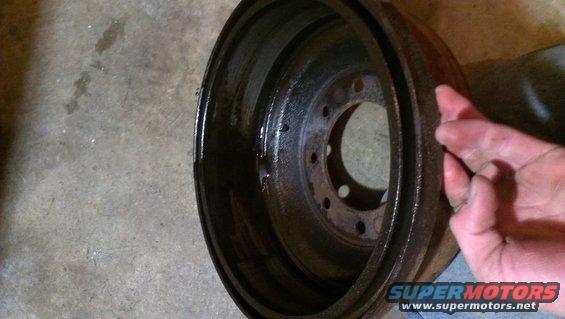 Close-up of a rusty brake drum with a hand touching the edge