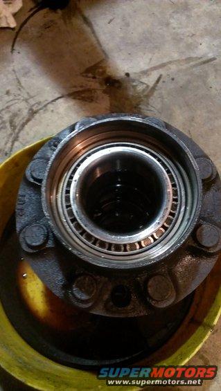 Wheel hub assembly with bearing, sitting in a yellow pan with oil
