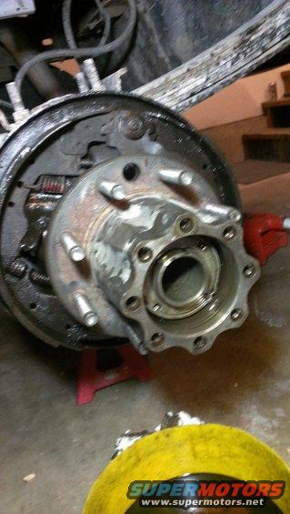 Close-up of a vehicle's rear axle hub and brake assembly, showing the drum, shoes, and hub with lug studs