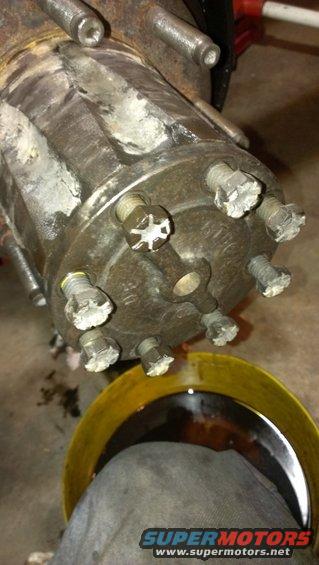 Wheel hub assembly with six lug nuts, some with white residue, over a yellow oil drain pan