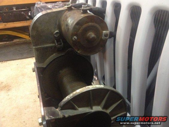 Winch motor and drum assembly mounted in front of a white radiator grille