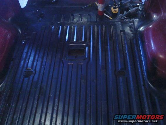 1978 Ford Bronco interior cargo area, dark ribbed floor, red side panel, fire extinguisher visible