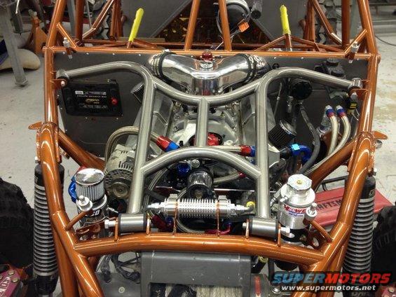 Engine bay of a custom dune buggy with a V8 engine, chrome intake, and orange roll cage