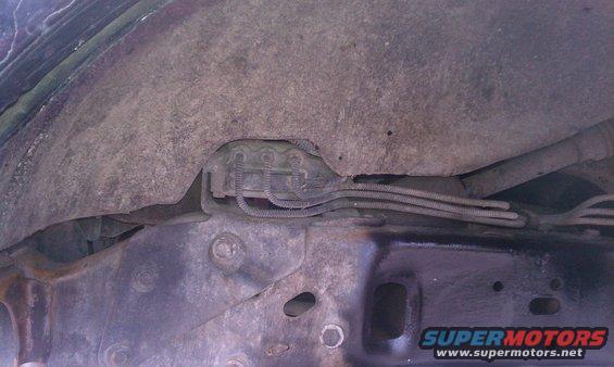 Vehicle underbody showing brake lines and suspension components, with a Supermotors.net watermark