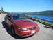 2003 Mercury Marauder - A red Ford Mustang is parked on a road overlooking a large body of water on a sunny day.