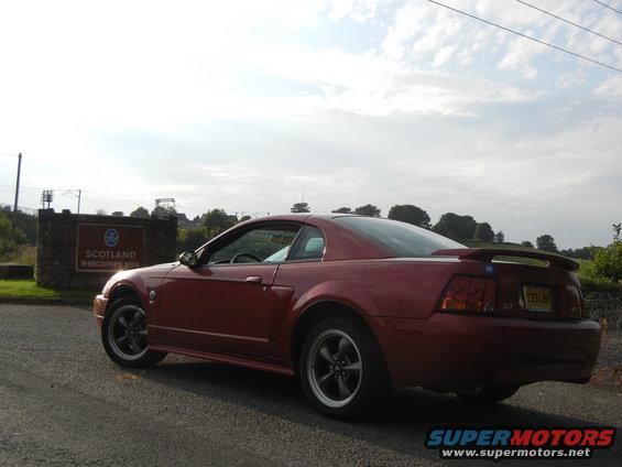 Red coupe parked near Scotland welcome sign