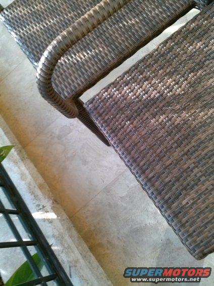 Wicker patio chairs on a tiled floor. A metal railing is visible on the left
