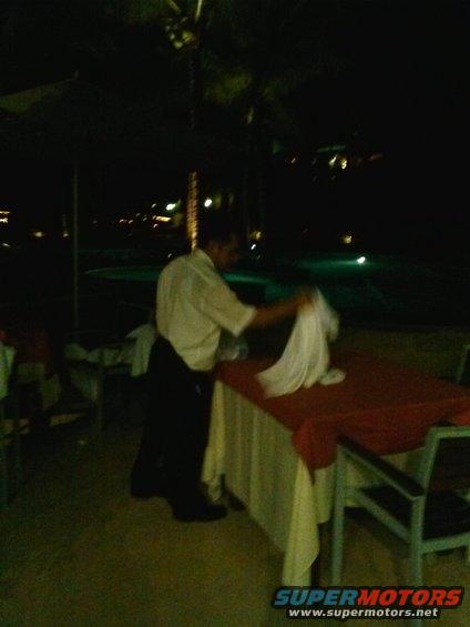 Waiter setting a table at night near a pool