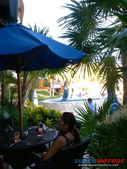 Outdoor seating area with palm trees, umbrella, and fountain