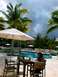 1960 Ford Falcon - A resort scene with a pool, palm trees, and people relaxing by the water.