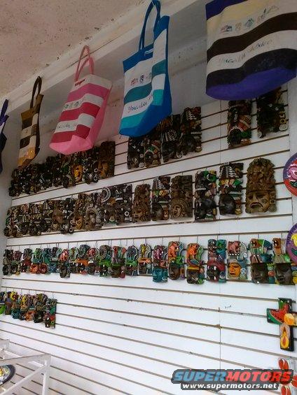 Wall display of carved wooden masks and woven bags in a shop