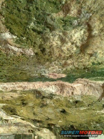 Rock formation with green moss and brown earth, Supermotors.net logo in lower right corner