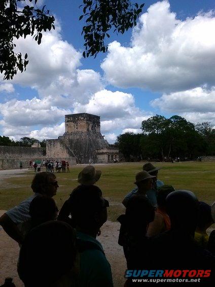 Chichen Itza pyramid with tourists under a cloudy sky