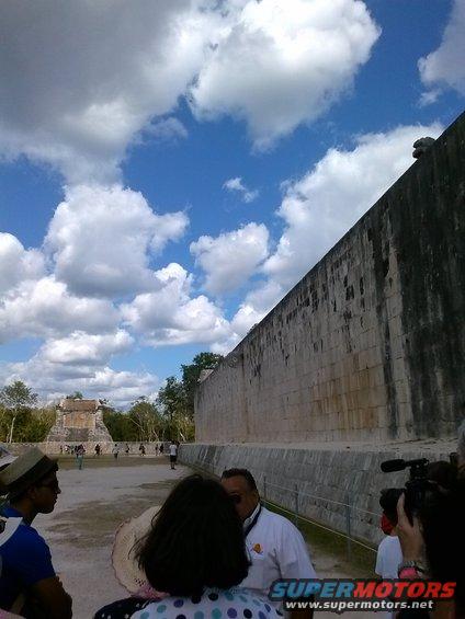 Tourists and a stone wall at Chichen Itza, Mexico, with a camera operator filming