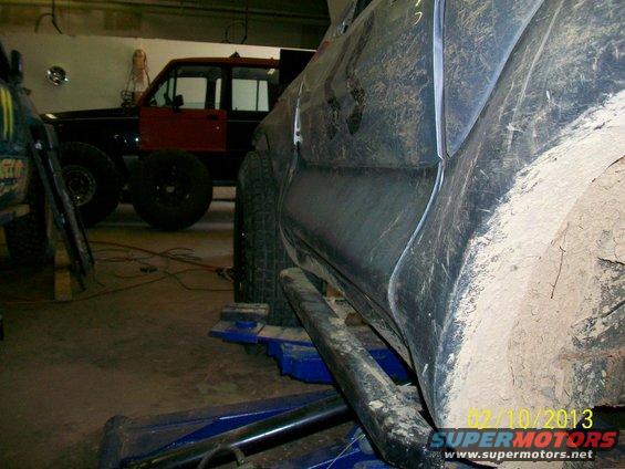 Muddy SUV on lift, another red SUV in background