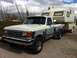 1991 Ford F-250 - Ford F-250 pickup truck with a camper in tow, showing peeling paint on the body.