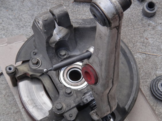 Disassembled car suspension component with brake rotor and bearing visible. Part number F500-5K170-A is stamped on metal