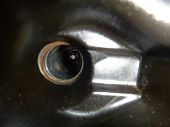 Close-up view into a spark plug hole with the plug tip visible inside
