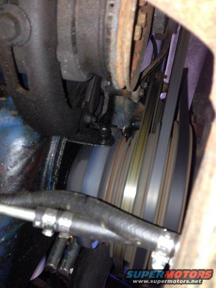 Engine belt pulleys with a black hose and metal clamps in the foreground