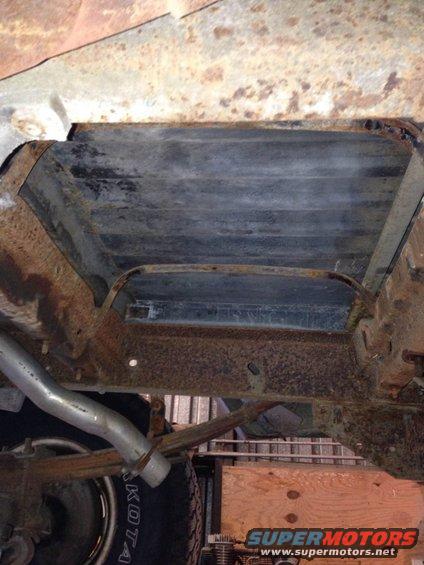 Undercarriage of a rusty vehicle with leaf springs and exhaust pipe visible