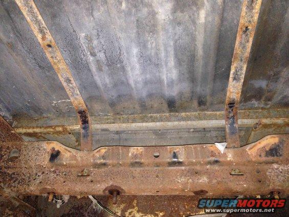 Underside of heavily rusted vehicle frame and bed supports