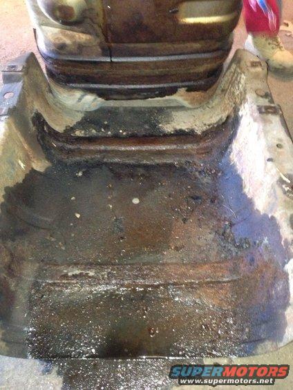 rusted out frame section with oil and grime