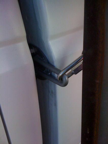 close-up of a metal chain and latch on a white vehicle door